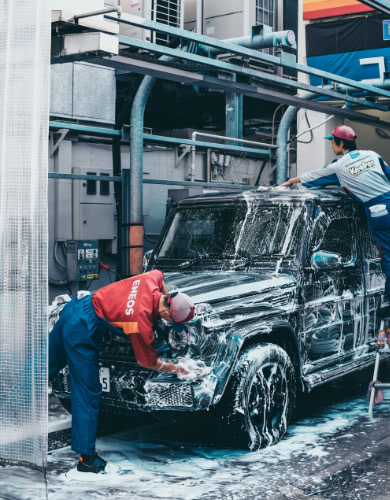 two people hand washing a soap covered jeep